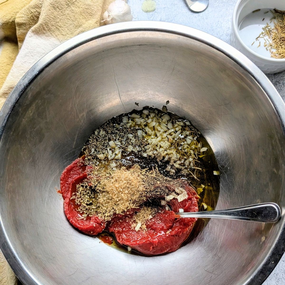 no salt pizza sauce ingredients in a bowl like tomato paste, brown sugar, basil, oregano, and rosemary.