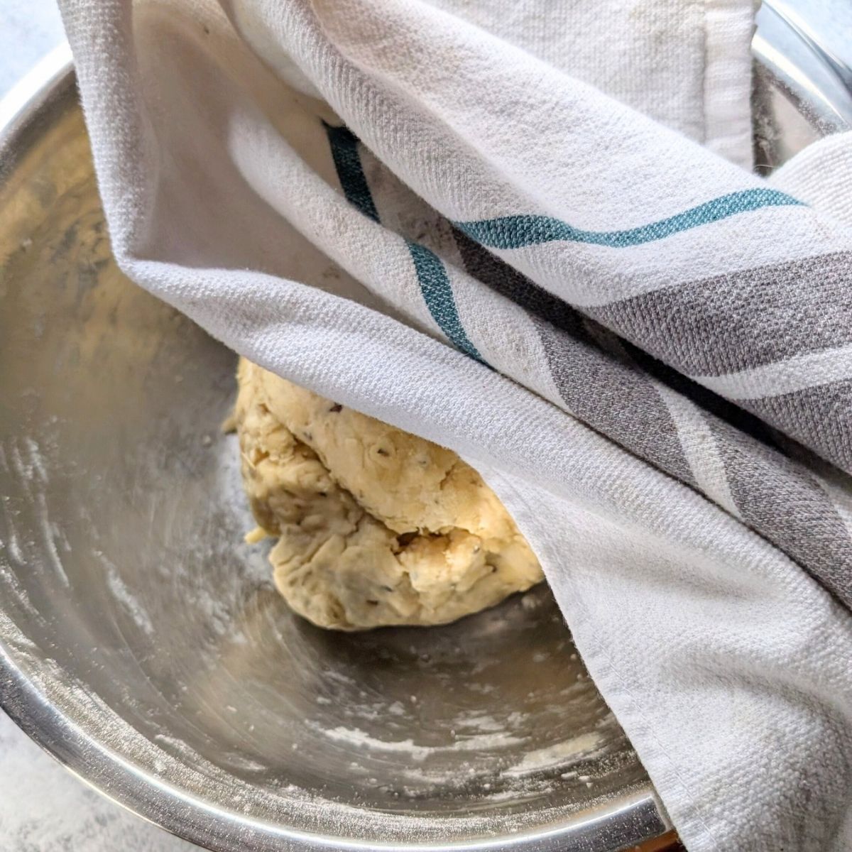 low sodium pizza dough in a bowl being covered by a tea towel to rise.