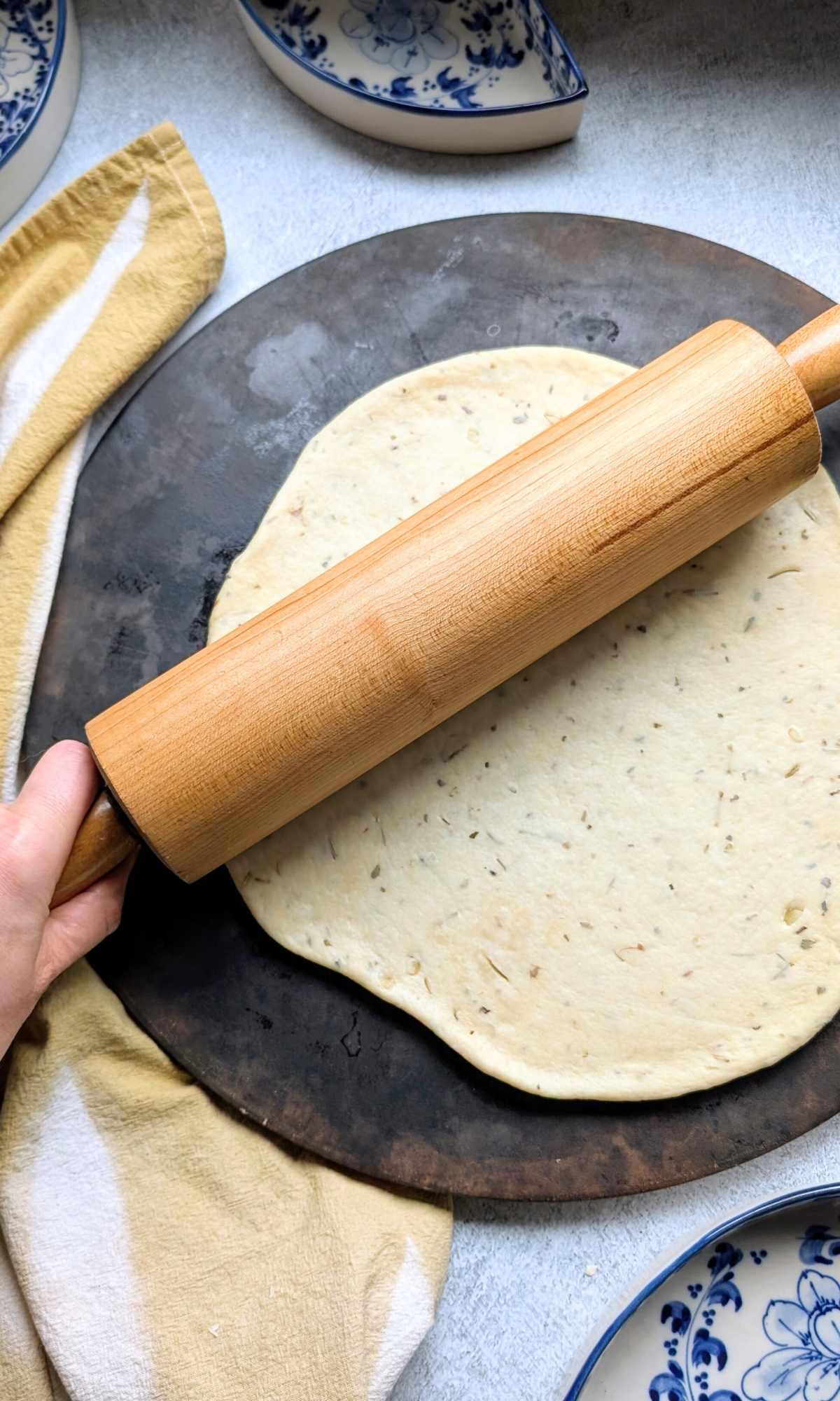 rolled out low sodium pizza dough recipe with a rolling pin on a pizza stone.