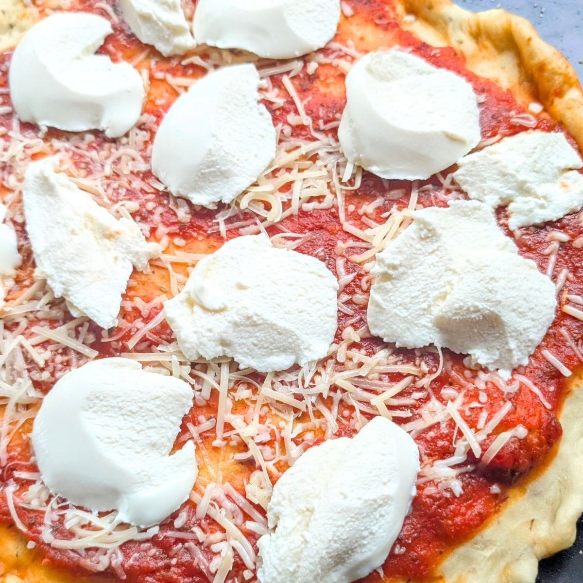 low sodium ricotta cheese dollops on salt free pizza dough and sauce