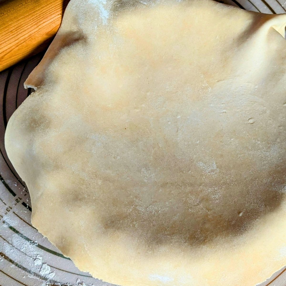 salt free pie crust draped over a baking dish with a rolling pin on a baking mat