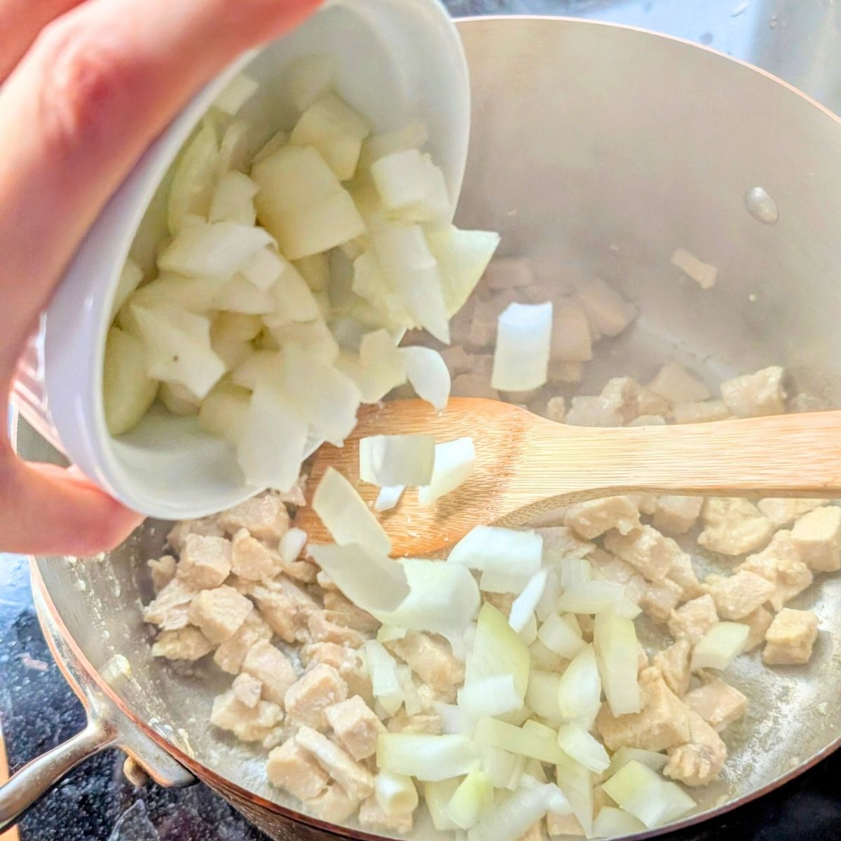 a dish of onions being added to chicken pot pie without salt for a low sodium comfort food dinner