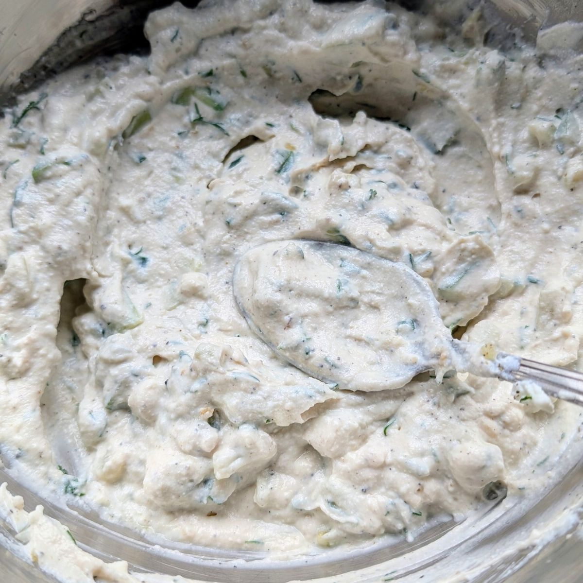 a spoon scooping up some no salt added yogurt sauce with low sodium yogurt and cucumbers