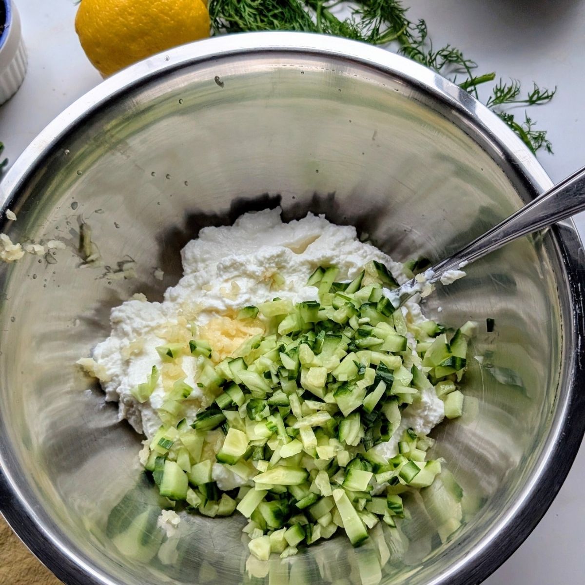 yogurt sauce with fresh garlic and chopped cucumber in a bowl to make low sodium condiment.