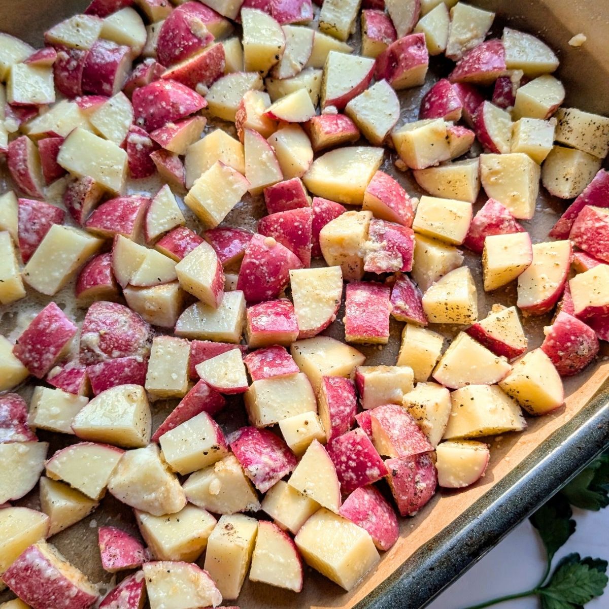 a sheet pan full of roasted red potatoes with spices ready for the oven