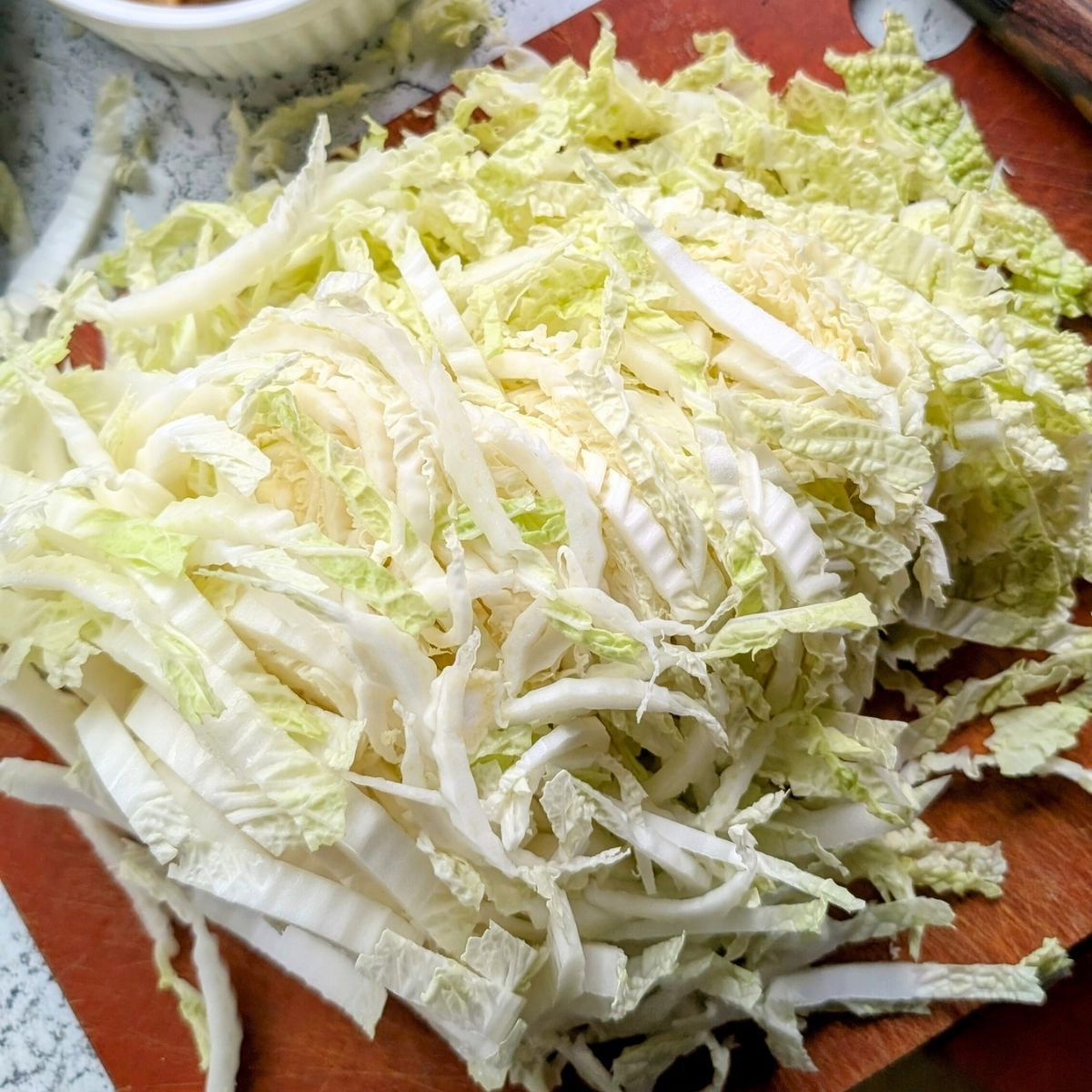 thinly shredded napa cabbage on a cutting board to make thai Crunch Salad