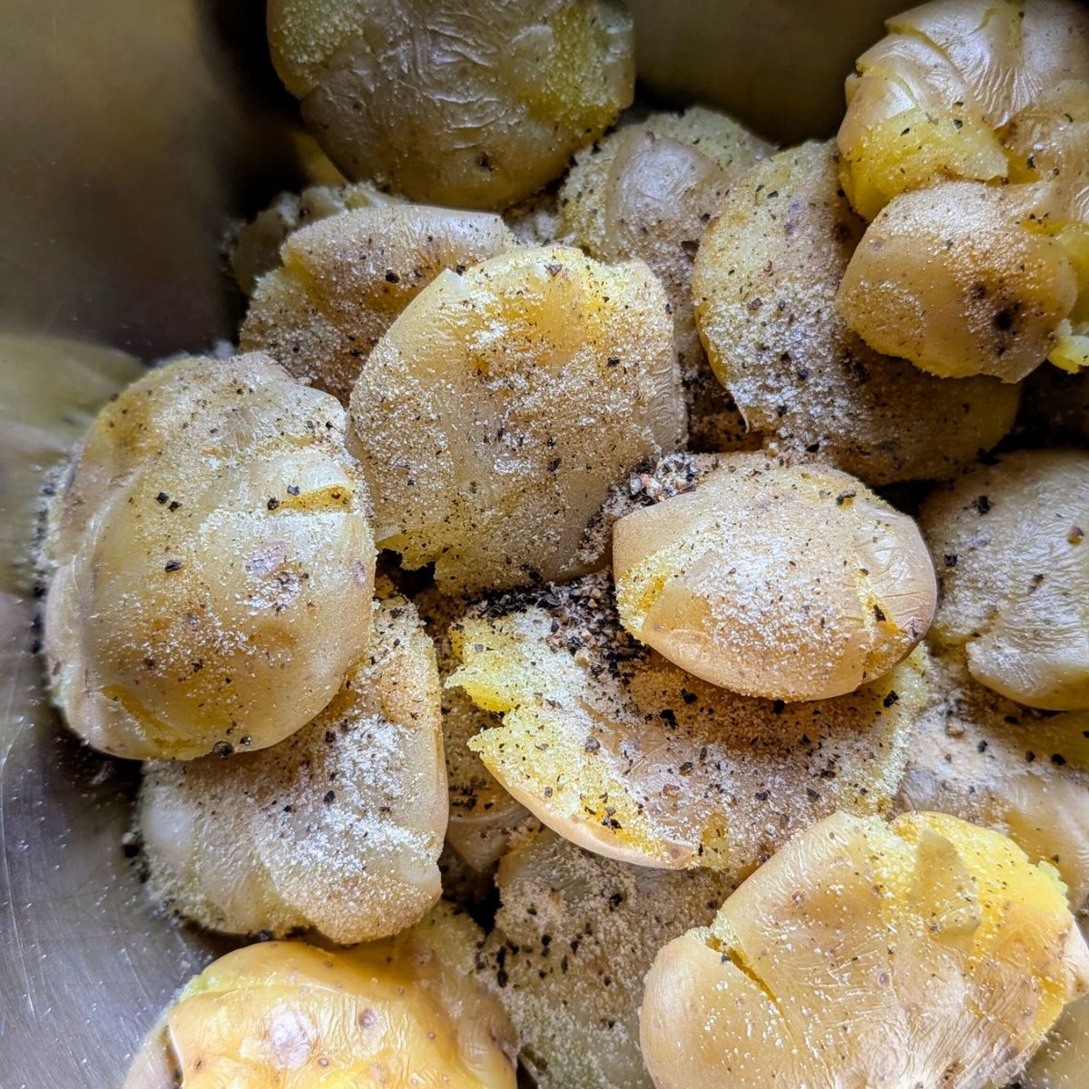 smashed potatoes in a bowl with salt free spices like onion and garlic powder and black pepper.
