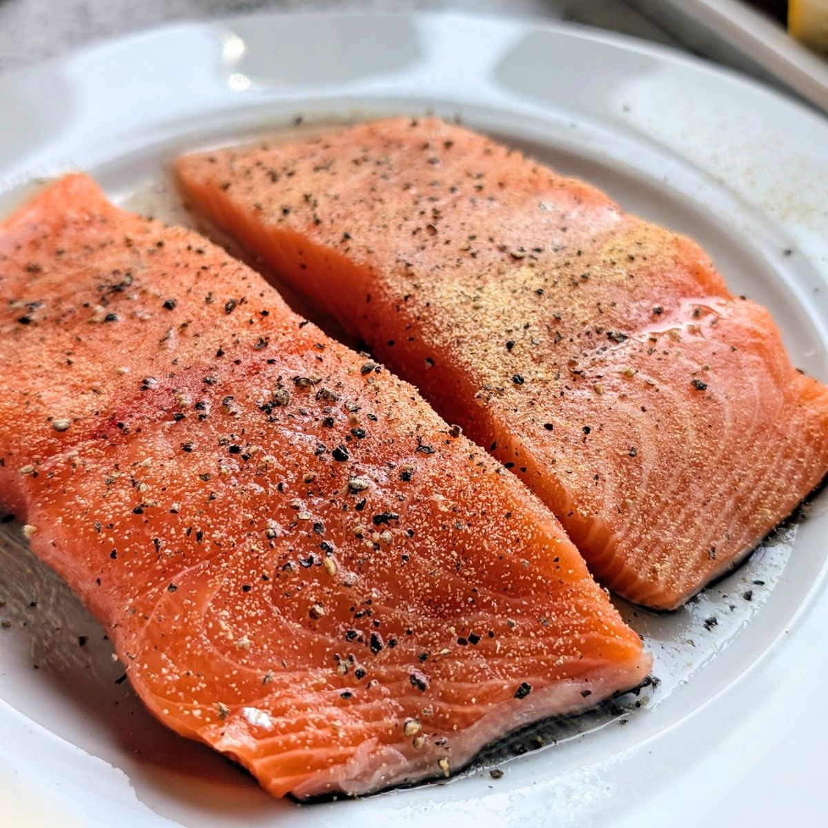 unsalted salmon filets with olive oil and black pepper resting before the grill.