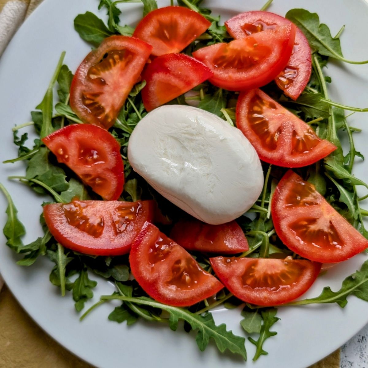 low salt burrata cheese in the center of a tomato and basil wreath