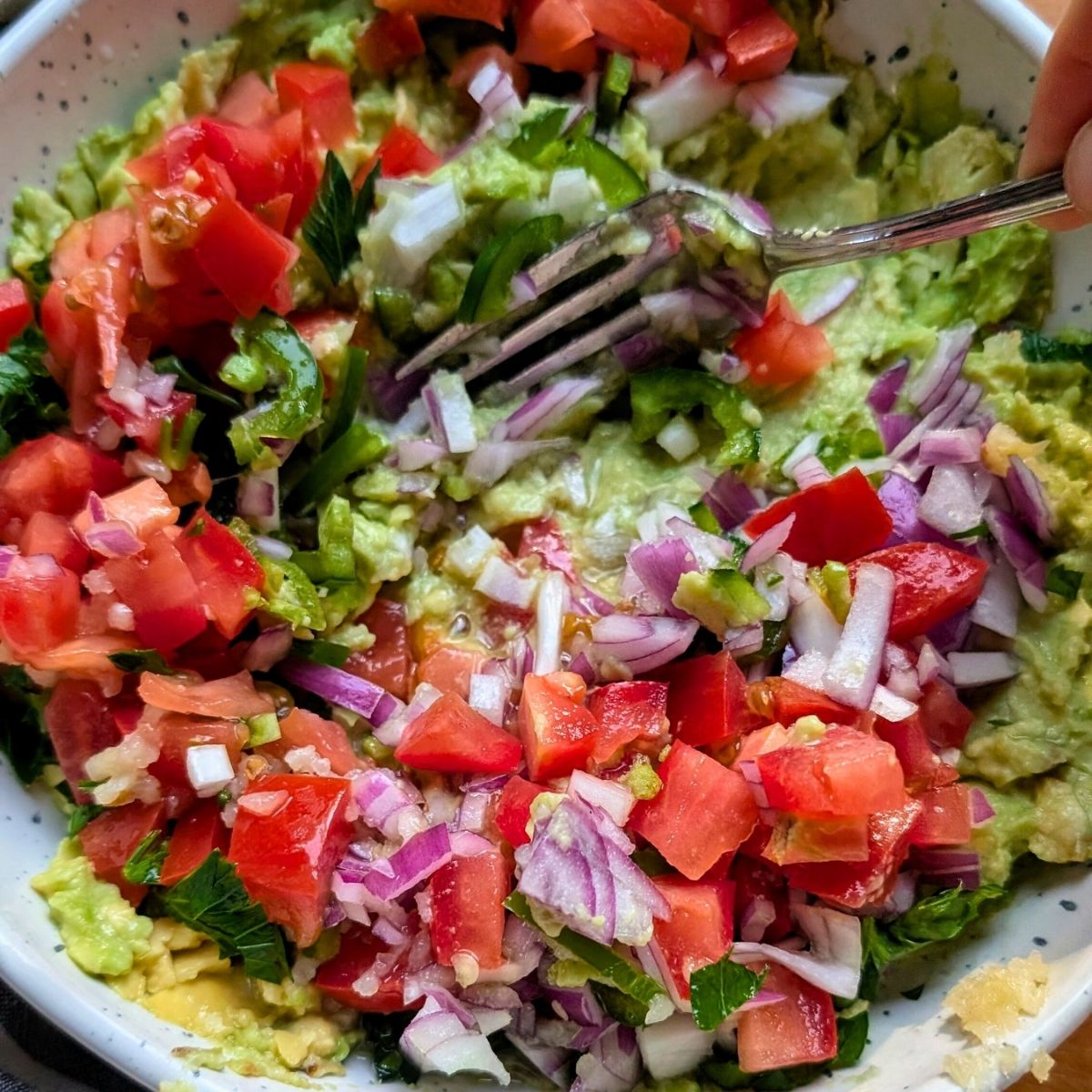 a fork mixing fresh guacamole without salt for an easy low sodium party appetizer for mexican recipes.