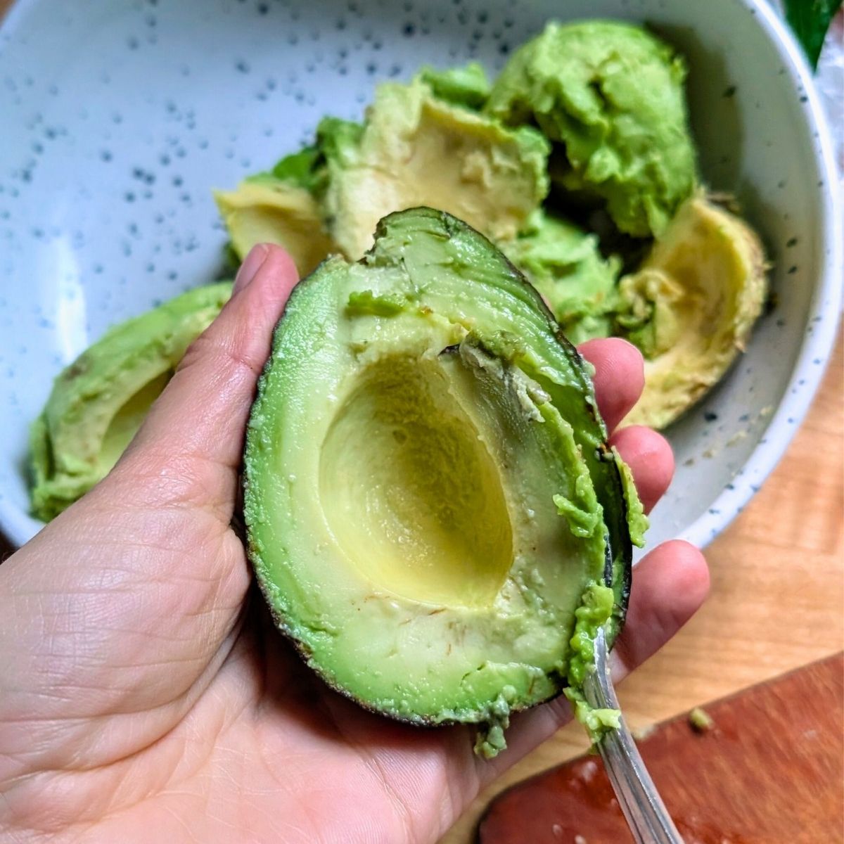 creamy ripe avocados in a bowl with a spoon.