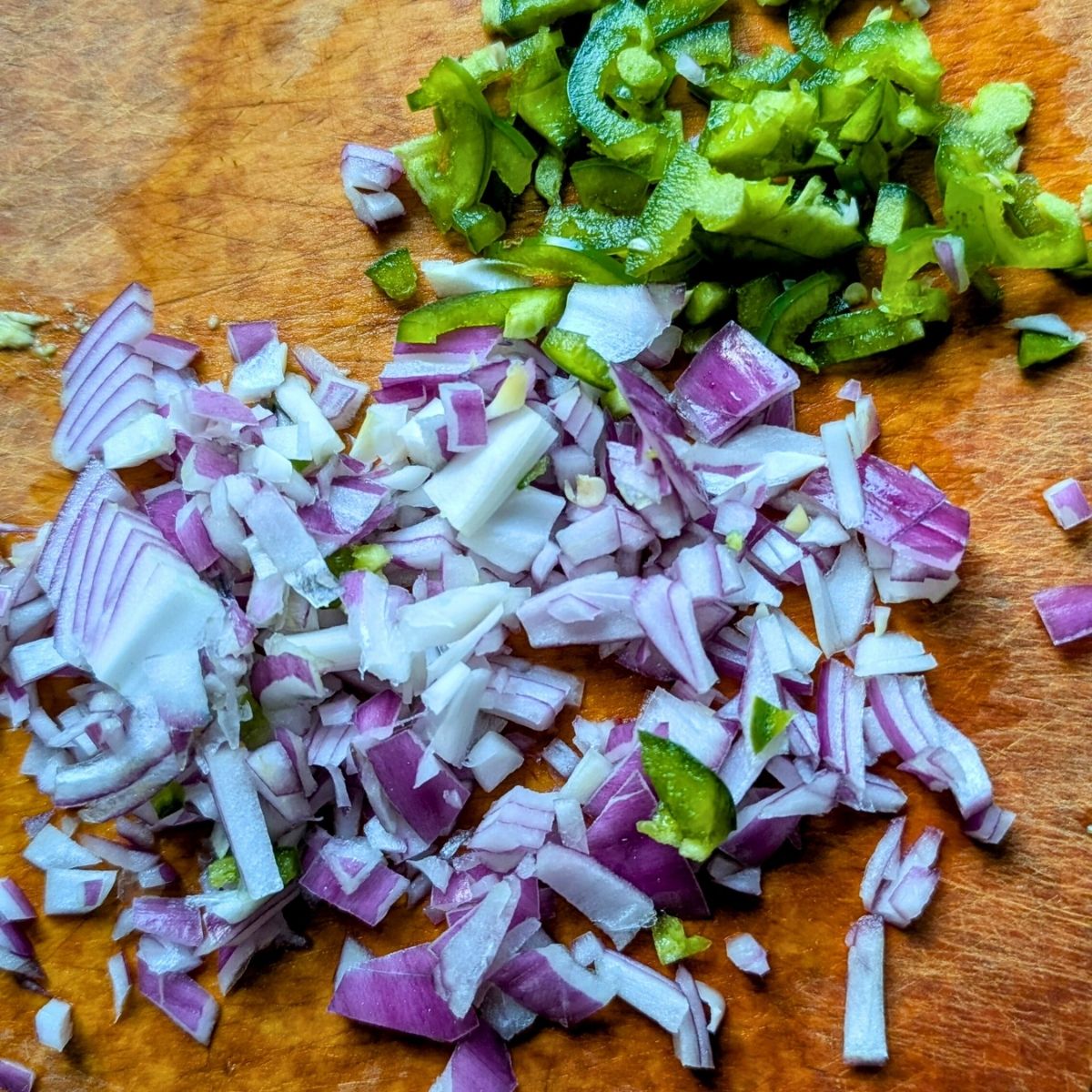chopped jalapeno pepper and red onion on a cutting board to make low sodium guac