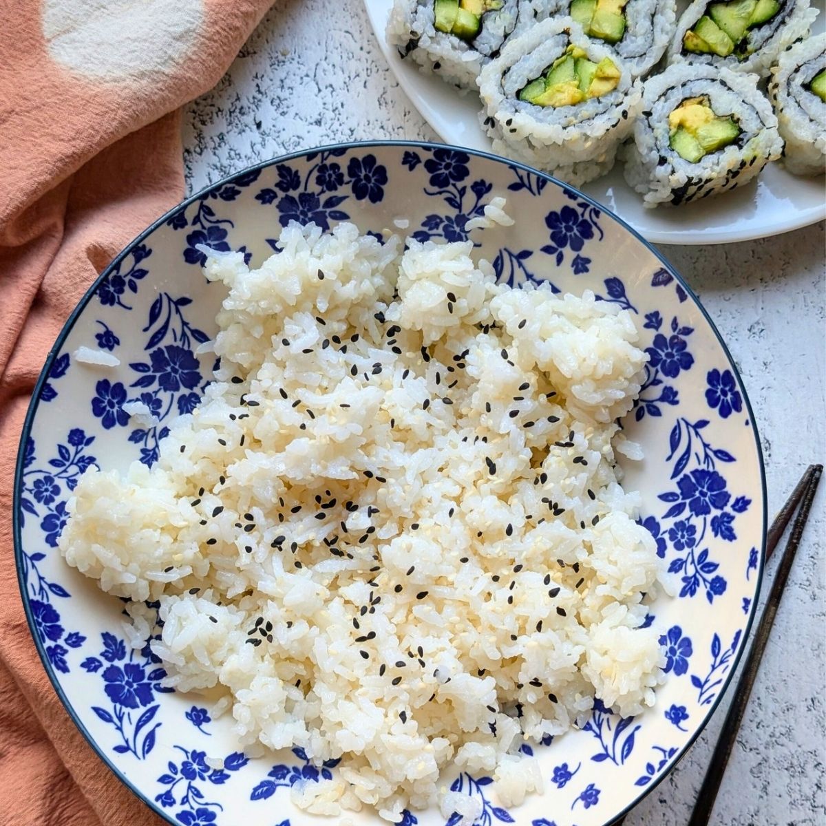 a bowl of sesame rice with sushi rolls in the background low sodium rice recipe