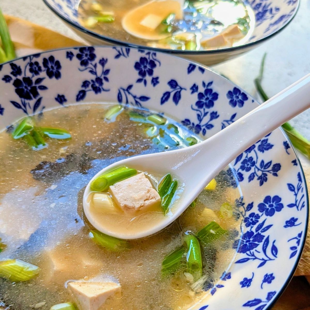 a bowl with low salt miso soup with tofu and green onions.
