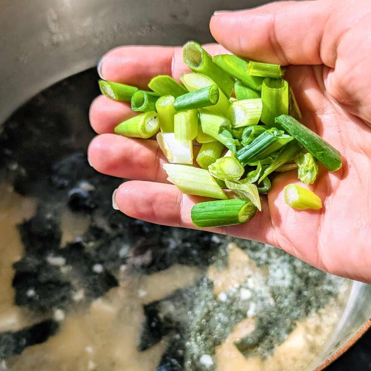 green onions being added to muso soup with low sodium miso paste.