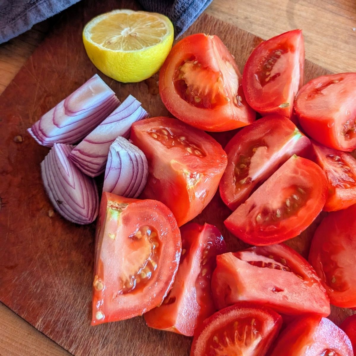 chopped tomatoes, red onion, and fresh lemon on a cutting board ready for the blender