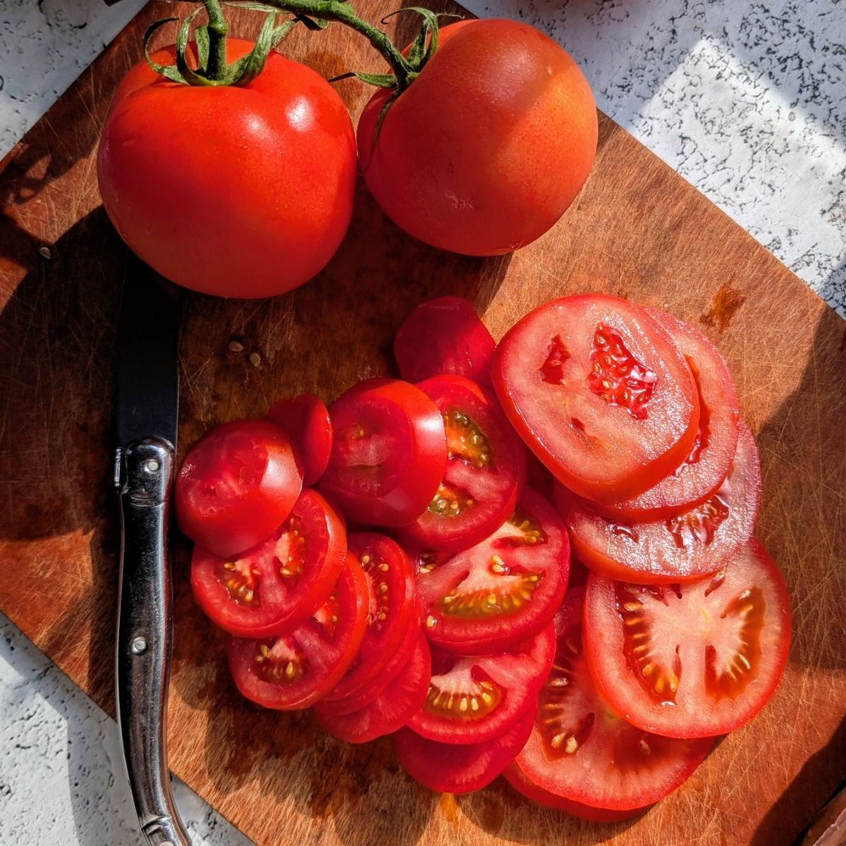 thinly sliced tomatoes on a cutting board to make a low sodium sandwich