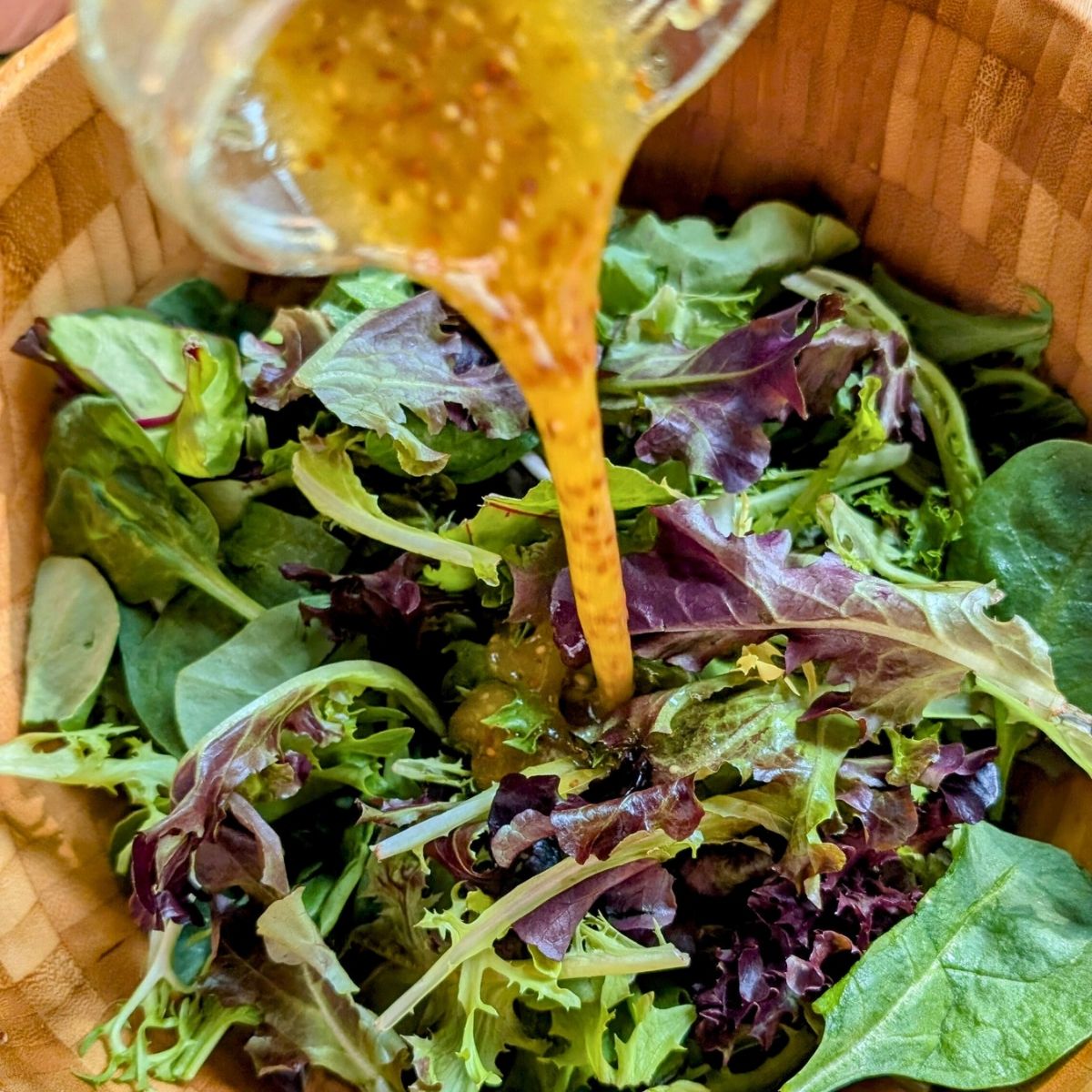 a bowl of mixed greens with salt free salad dressing on the top.