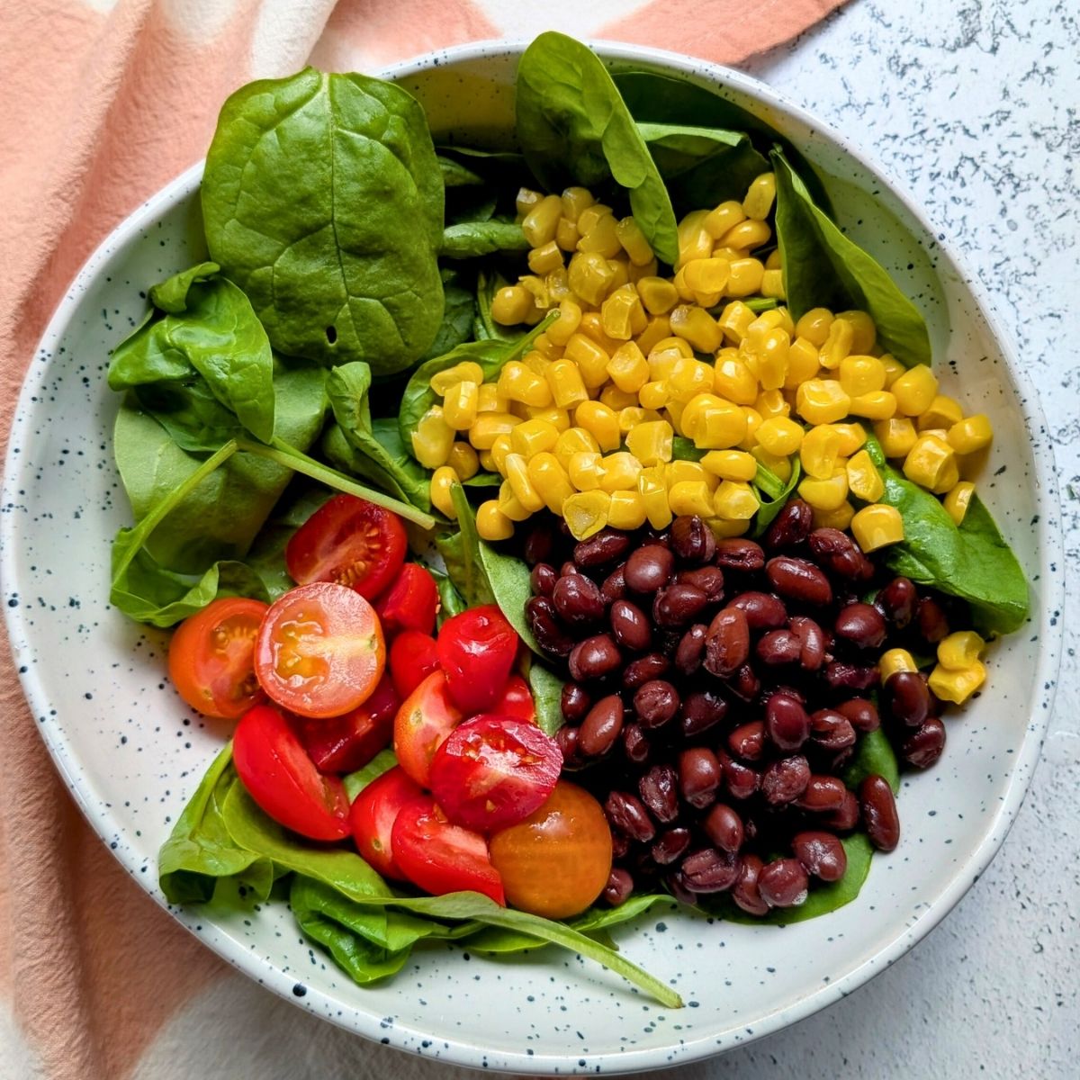a bowl of baby spinach, fresh corn, no salt added black beans, and tomatoes to make a low sodium steak bowl.
