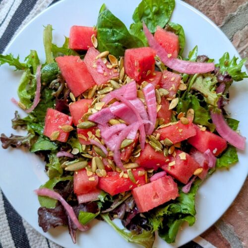 low sodium salad with watermelon, mixed greens, and pumpkin seeds on a plate.