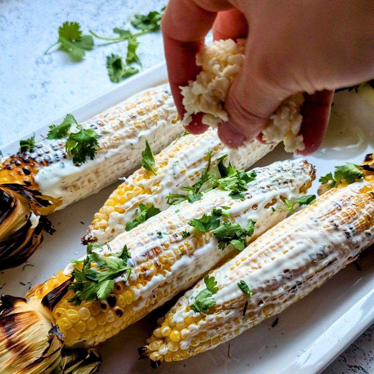 a hand sprinkling cheese and cilantro on top of low sodium mexican corn.