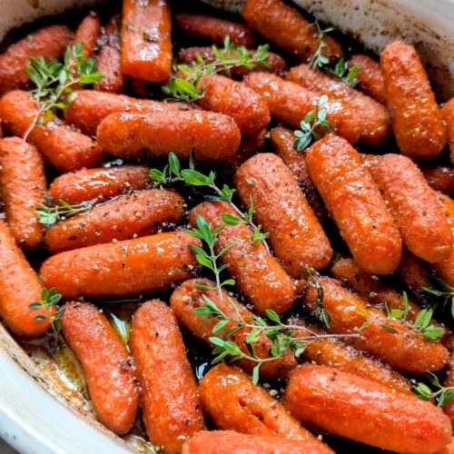 low sodium roasted baby carrots in a baking dish with fresh herbs and a honey worcestershire dressing