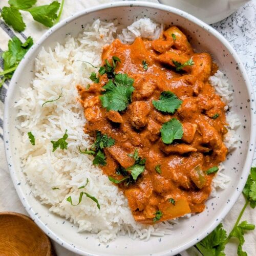 a bowl of low sodium indian chicken and rice with fresh herbs and spices.