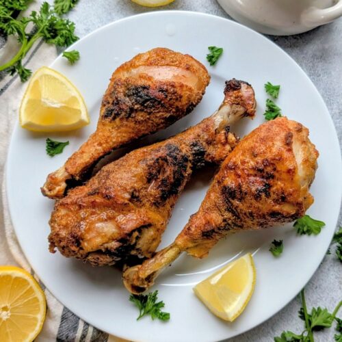 a plate of low sodium chicken legs with lemons and fresh herbs like parsley on a plate